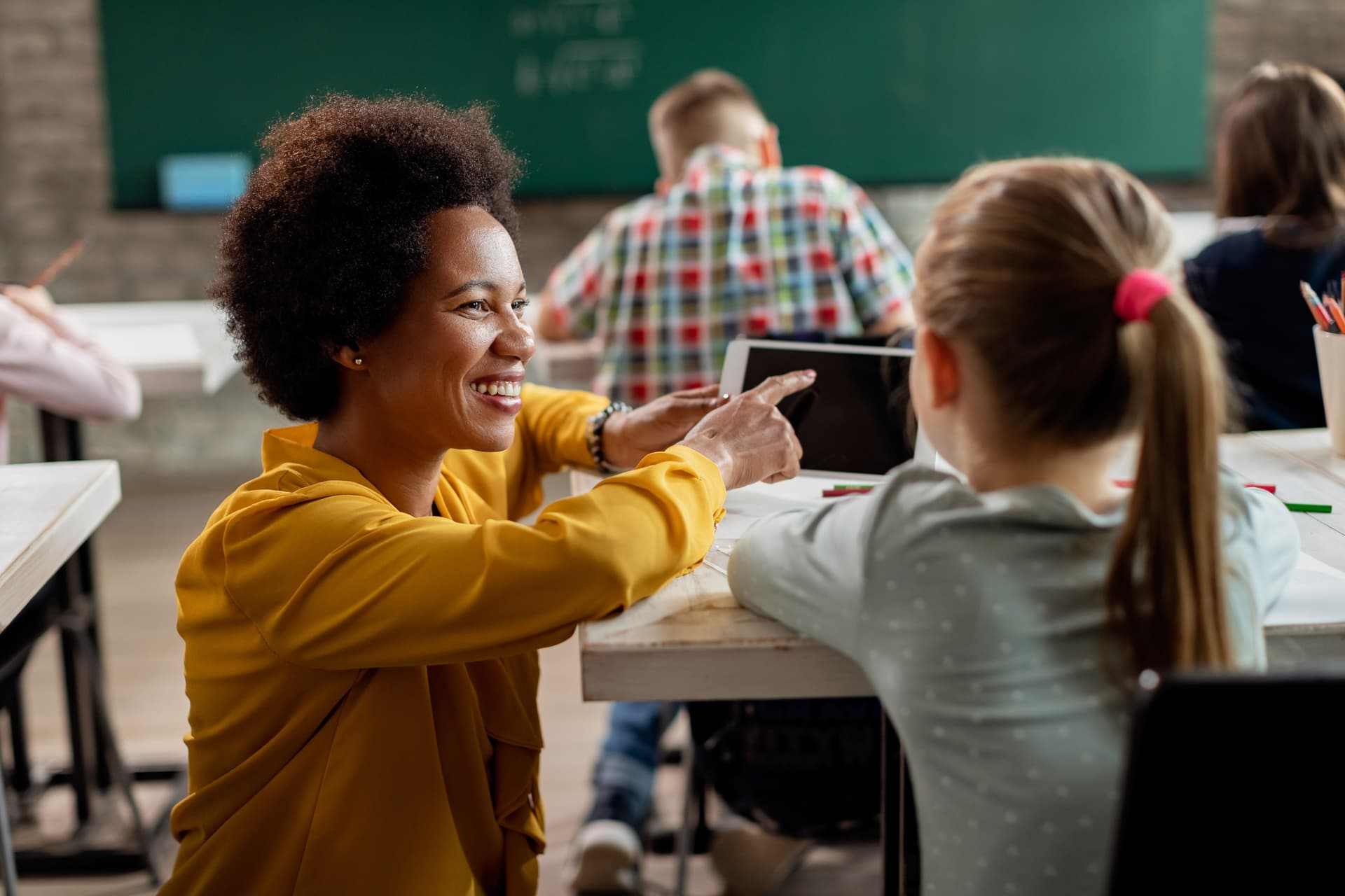 Teacher helping a student with a tablet in a classroom